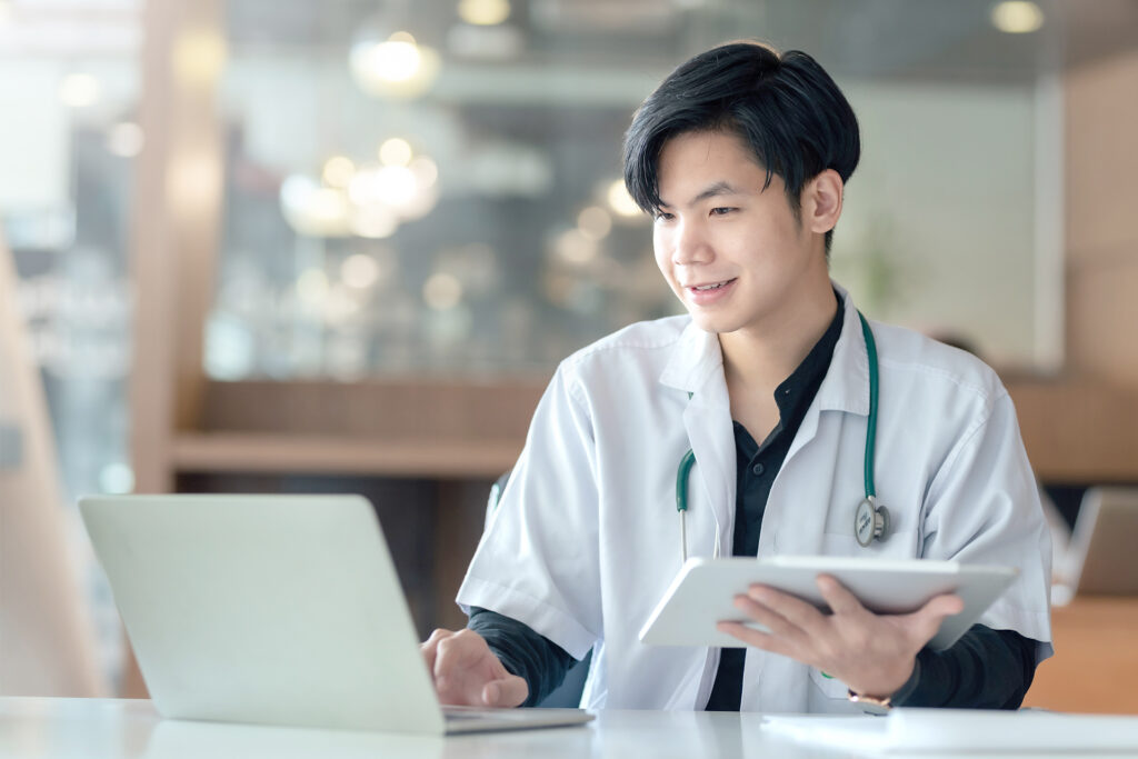Asian male internship doctor sitting using laptop computer in the office.